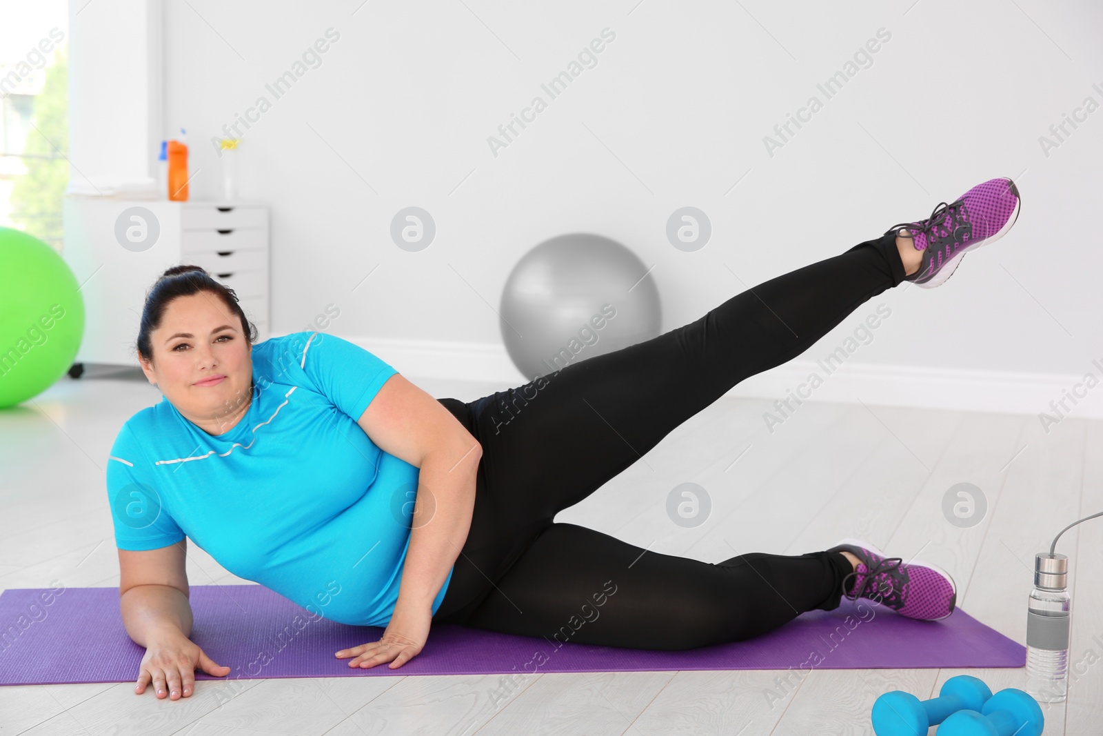 Photo of Overweight woman doing exercise on mat in gym