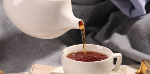 Photo of Pouring aromatic tea into cup in bed, closeup