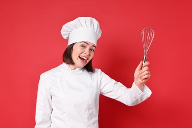 Happy confectioner holding whisk on red background