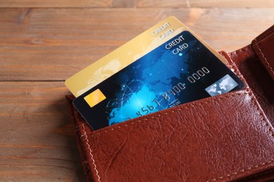 Photo of Credit cards in leather wallet on wooden table, closeup