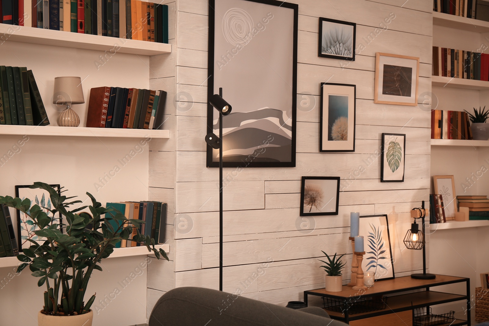 Photo of Home library interior with collection of different books on shelves and beautiful pictures