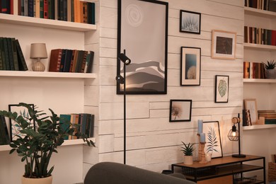 Photo of Home library interior with collection of different books on shelves and beautiful pictures