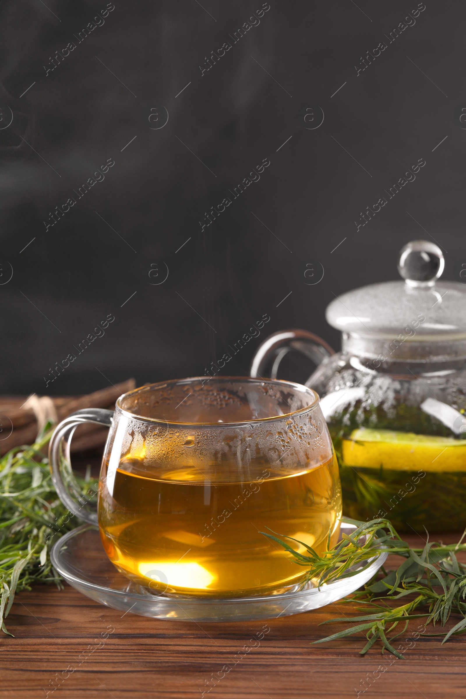 Photo of Homemade herbal tea and fresh tarragon leaves on wooden table