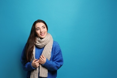 Photo of Young woman wearing warm clothes on color background, space for text. Winter season