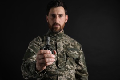 Photo of Soldier holding hand grenade on black background, selective focus. Military service
