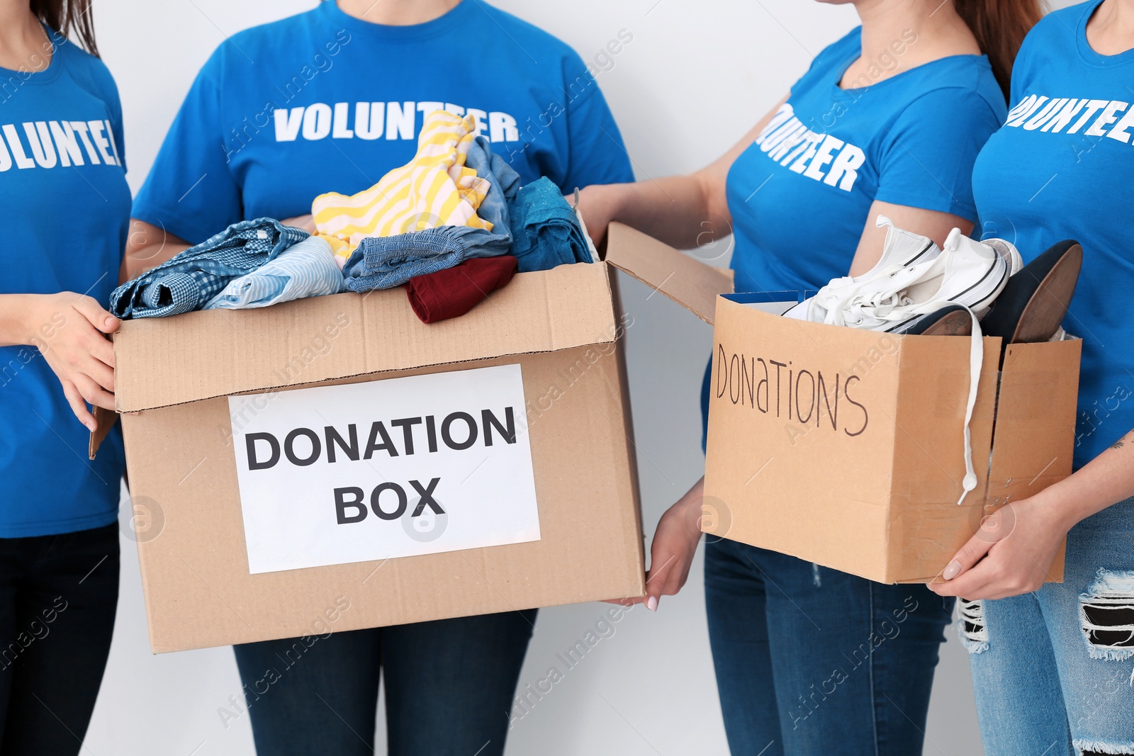 Photo of Team of volunteers with donation boxes on light background