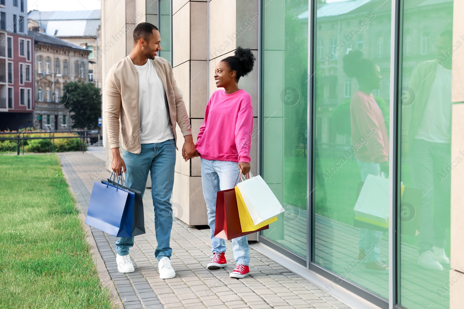 Photo of Family shopping. Happy couple with colorful bags near mall outdoors