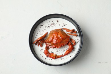 Delicious boiled crab with cream sauce in bowl on white table, top view