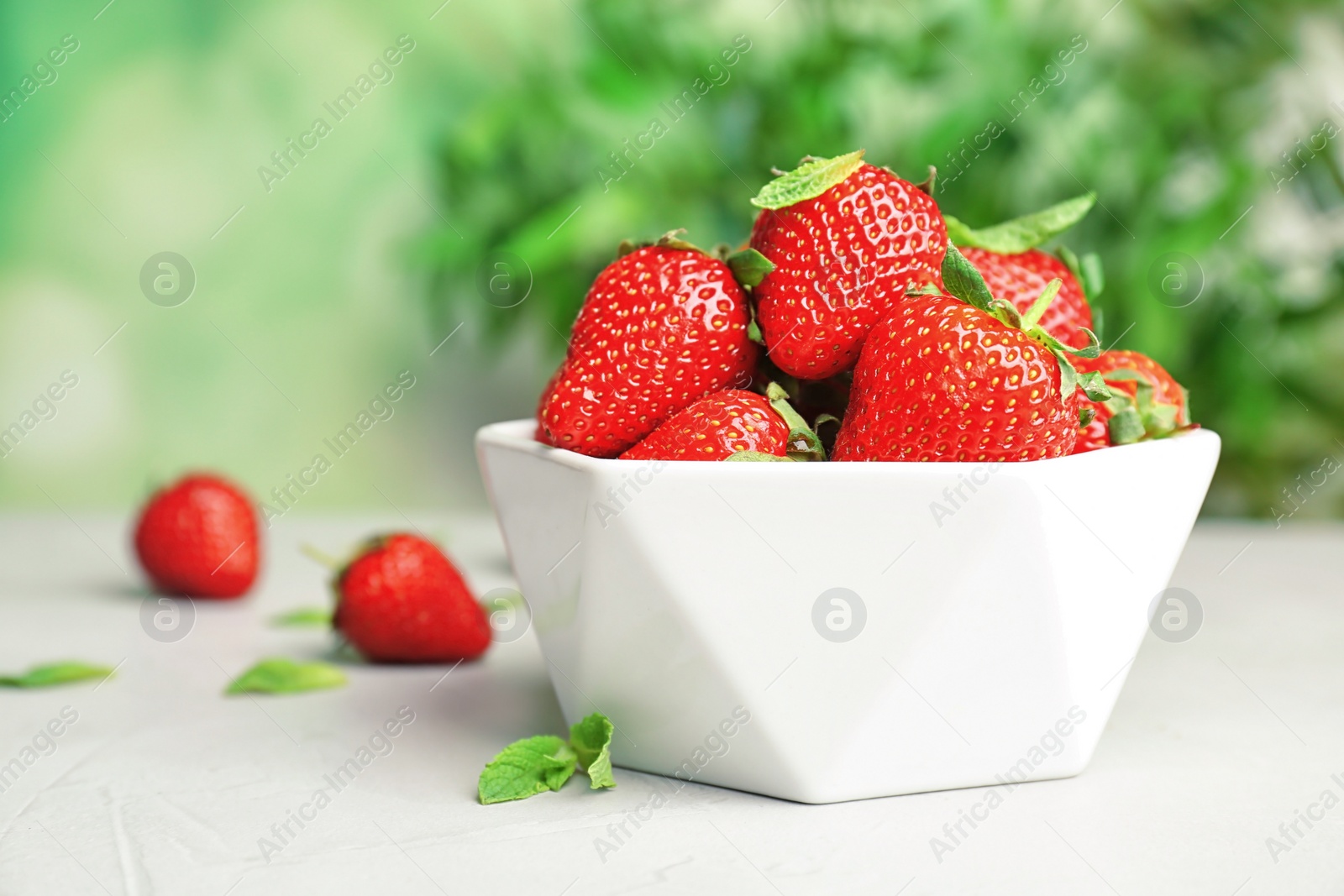 Photo of Bowl with ripe red strawberries on table