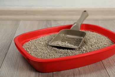 Photo of Cat tray with clumping litter and scoop on floor indoors, closeup