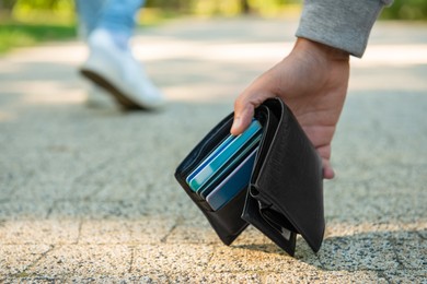 Photo of Man picking lost wallet from ground outdoors, closeup. Space for text