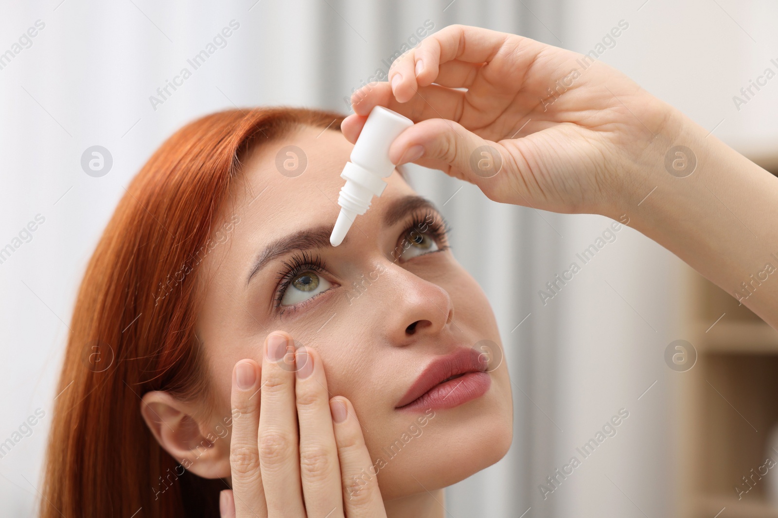 Photo of Woman applying medical eye drops at home