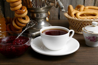 Photo of Composition with hot tea and delicious ring shaped Sushki (dry bagels) on wooden table
