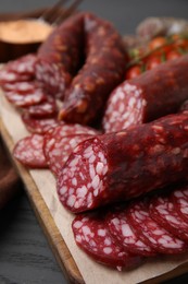 Photo of Delicious smoked sausages on black wooden table, closeup