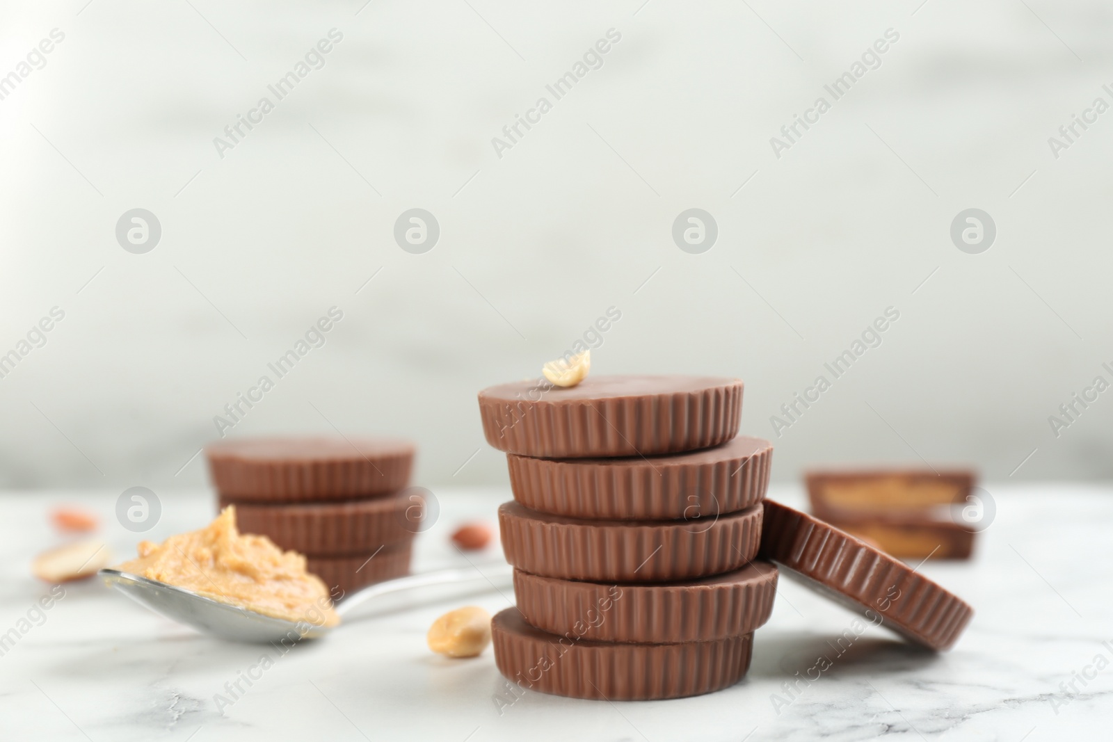 Photo of Delicious peanut butter cups on white marble table, space for text