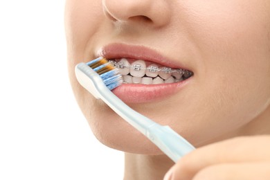 Woman with dental braces cleaning teeth on white background, closeup
