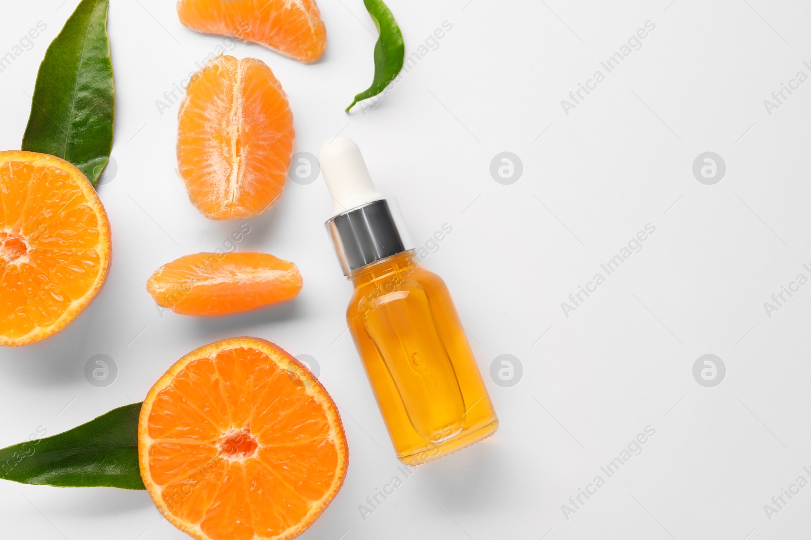 Photo of Aromatic tangerine essential oil in bottle, leaves and citrus fruits on white table, flat lay. Space for text