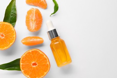 Photo of Aromatic tangerine essential oil in bottle, leaves and citrus fruits on white table, flat lay. Space for text