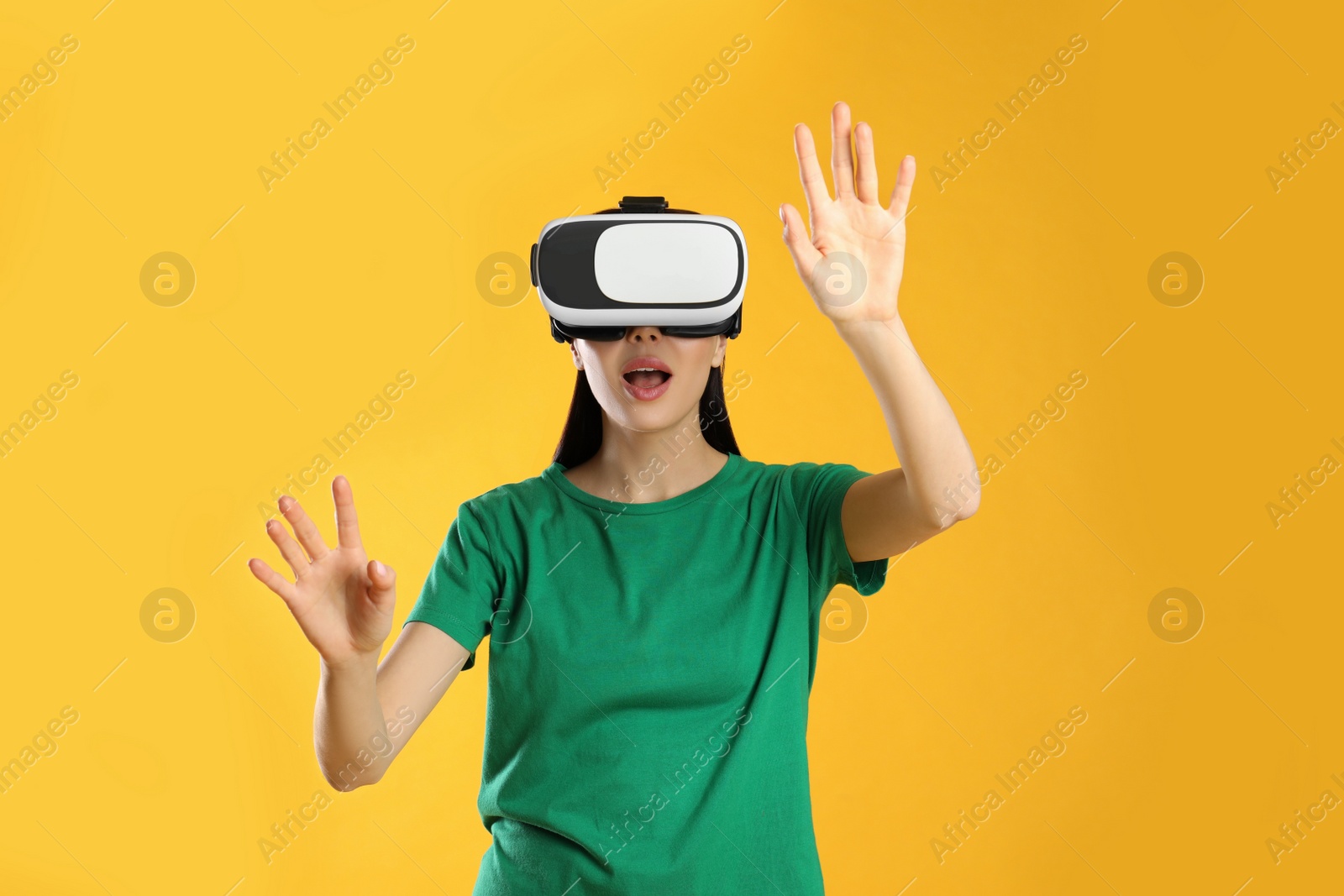 Photo of Woman using virtual reality headset on yellow background