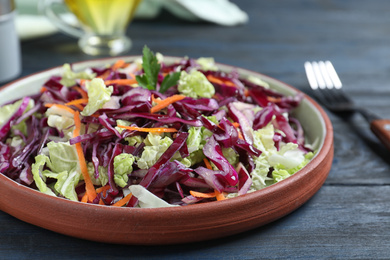 Photo of Fresh cabbage salad served on blue wooden table, closeup
