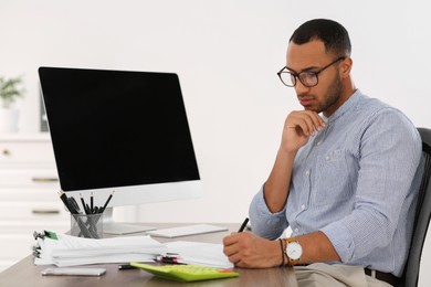 Photo of Businessman working with documents at wooden table in office