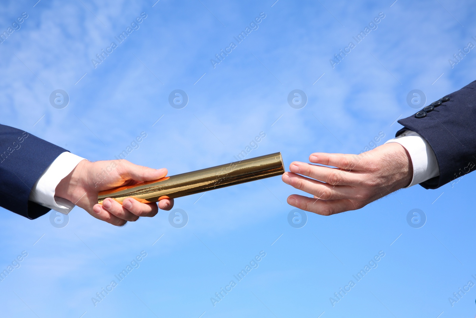 Photo of Businessman passing baton to his partner against blue sky, closeup