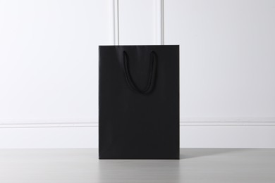 Black paper bag on white wooden table