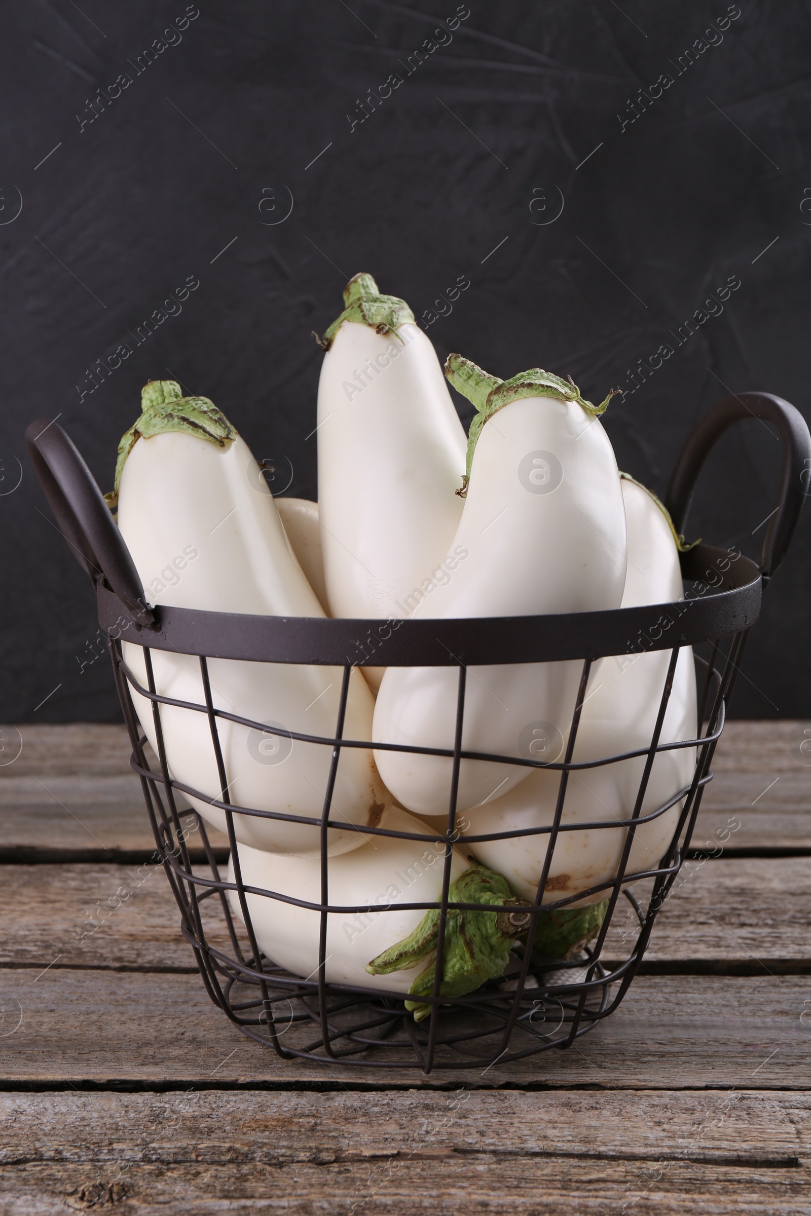 Photo of Fresh white eggplants in metal basket on wooden table