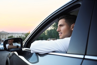 Photo of Handsome man in his modern car, view from outside