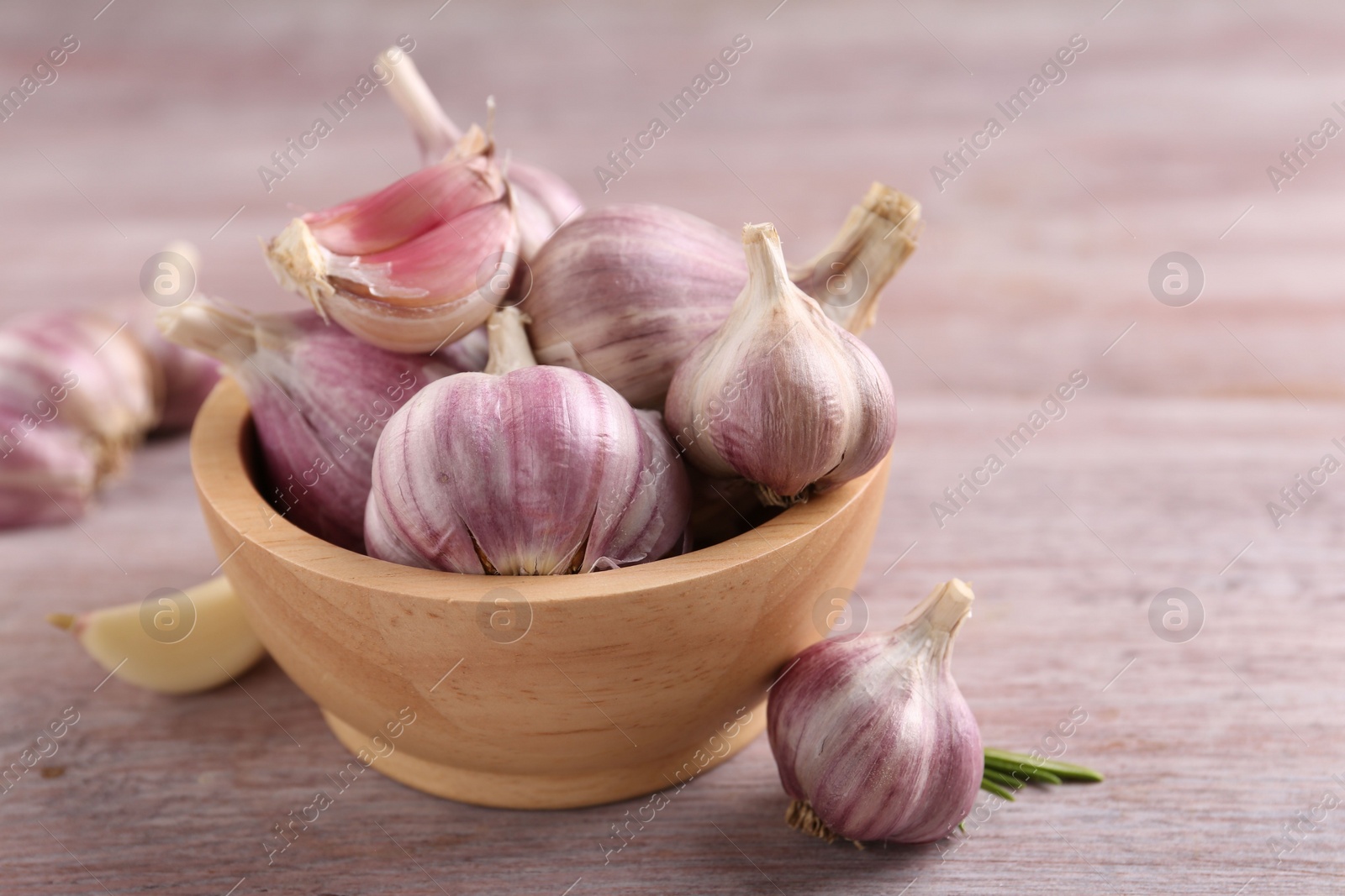 Photo of Bowl with fresh garlic on wooden table, closeup