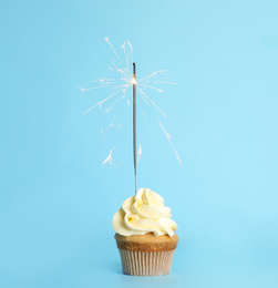Photo of Birthday cupcake with sparkler on light blue background