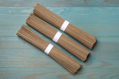 Uncooked buckwheat noodles (soba) on light blue wooden table, flat lay