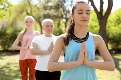 Group of women practicing yoga in park on sunny day