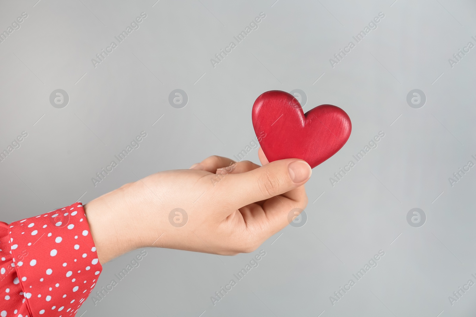 Photo of Woman holding red heart on grey background, closeup. Happy Valentine's Day