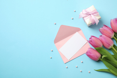 Photo of Flat lay composition with tulips and card on light blue background, space for text. Happy Mother's day