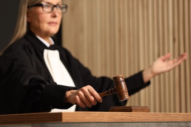 Judge striking mallet at wooden table indoors, selective focus. Space for text