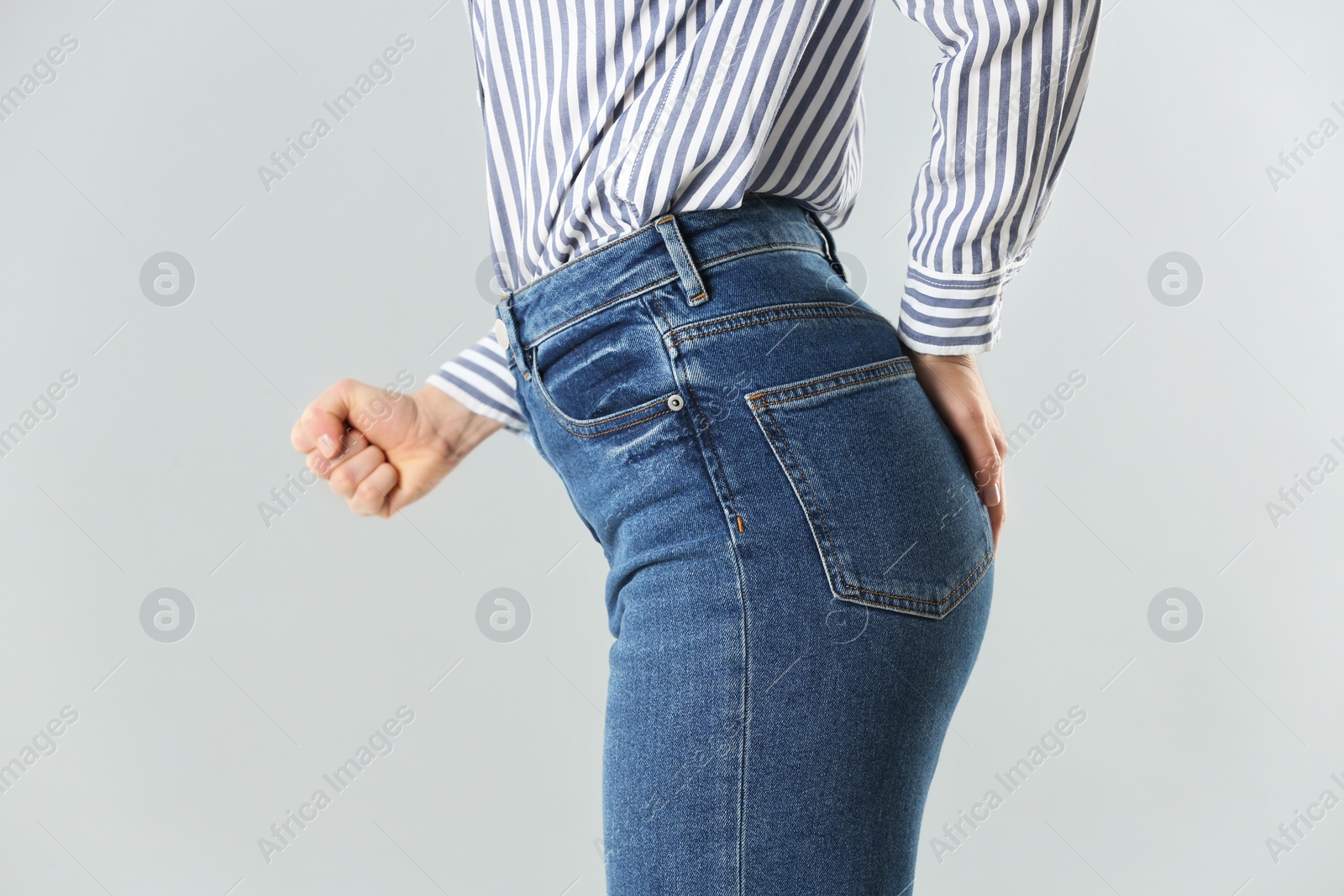 Photo of Woman suffering from hemorrhoid on light grey background, closeup