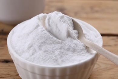Photo of Bowl of fructose powder on wooden table, closeup