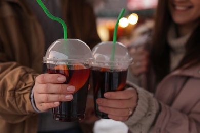 Photo of Friends with cups of mulled wine outdoors, closeup