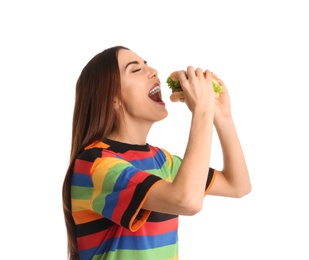 Young woman eating tasty burger on white background