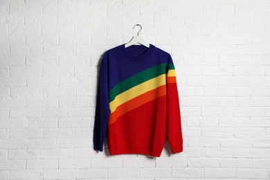 Photo of Hanger with stylish sweater on brick wall