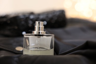 Photo of Bottle of perfume on black leather jacket, closeup