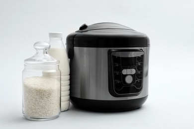 Photo of Modern electric multi cooker, rice and milk on light background