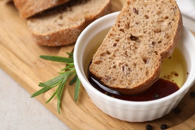 Photo of Bowl of organic balsamic vinegar with oil served with spices and bread slices on beige table, closeup