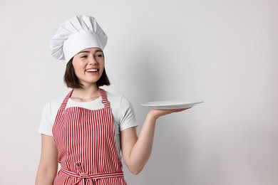 Photo of Happy confectioner with plate on light grey background