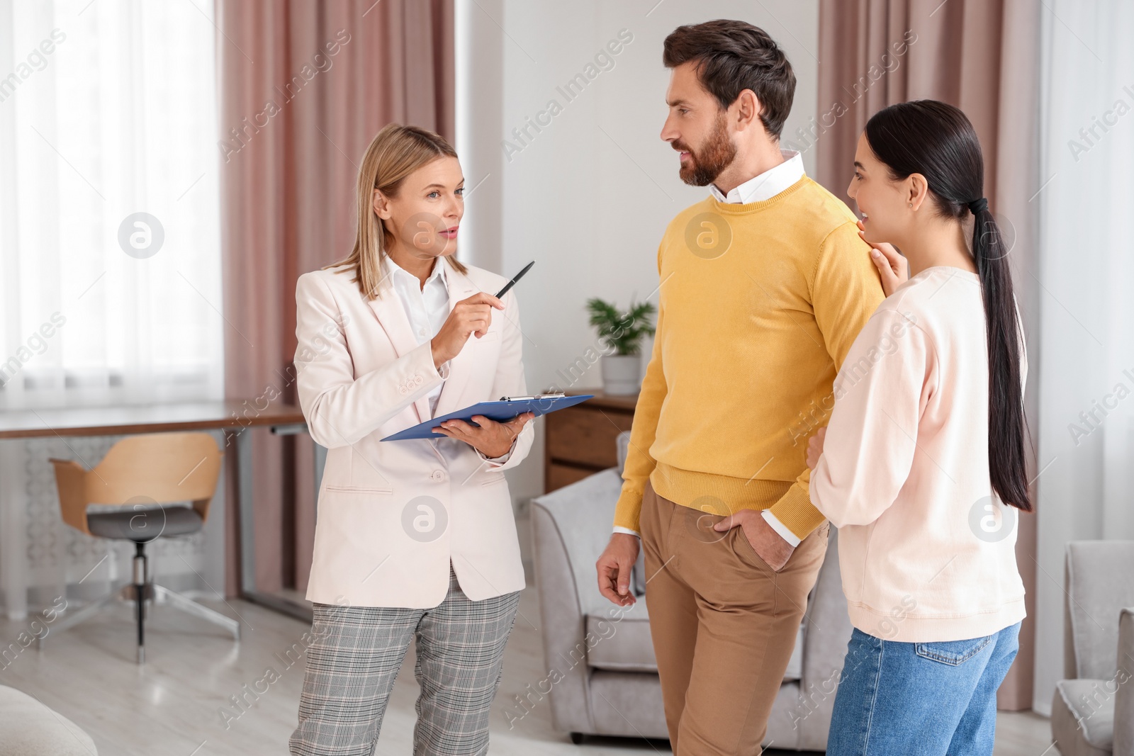 Photo of Real estate agent working with couple in new apartment