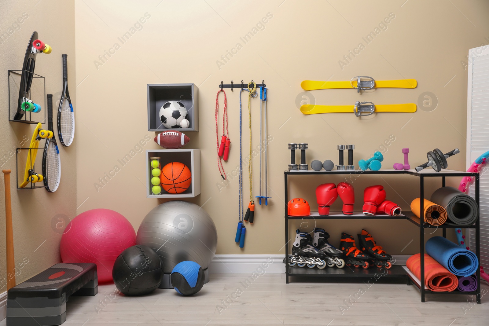 Photo of Many different sports equipment in room with beige walls