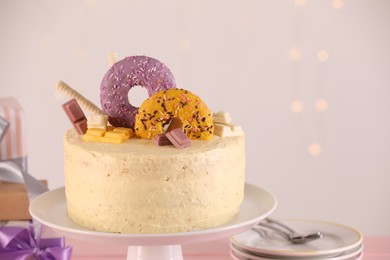 Photo of Delicious cake decorated with sweets against blurred lights, space for text