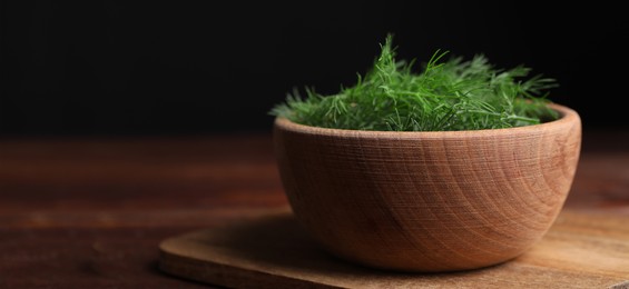 Image of Fresh dill in bowl on wooden table against black background. Banner design with space for text