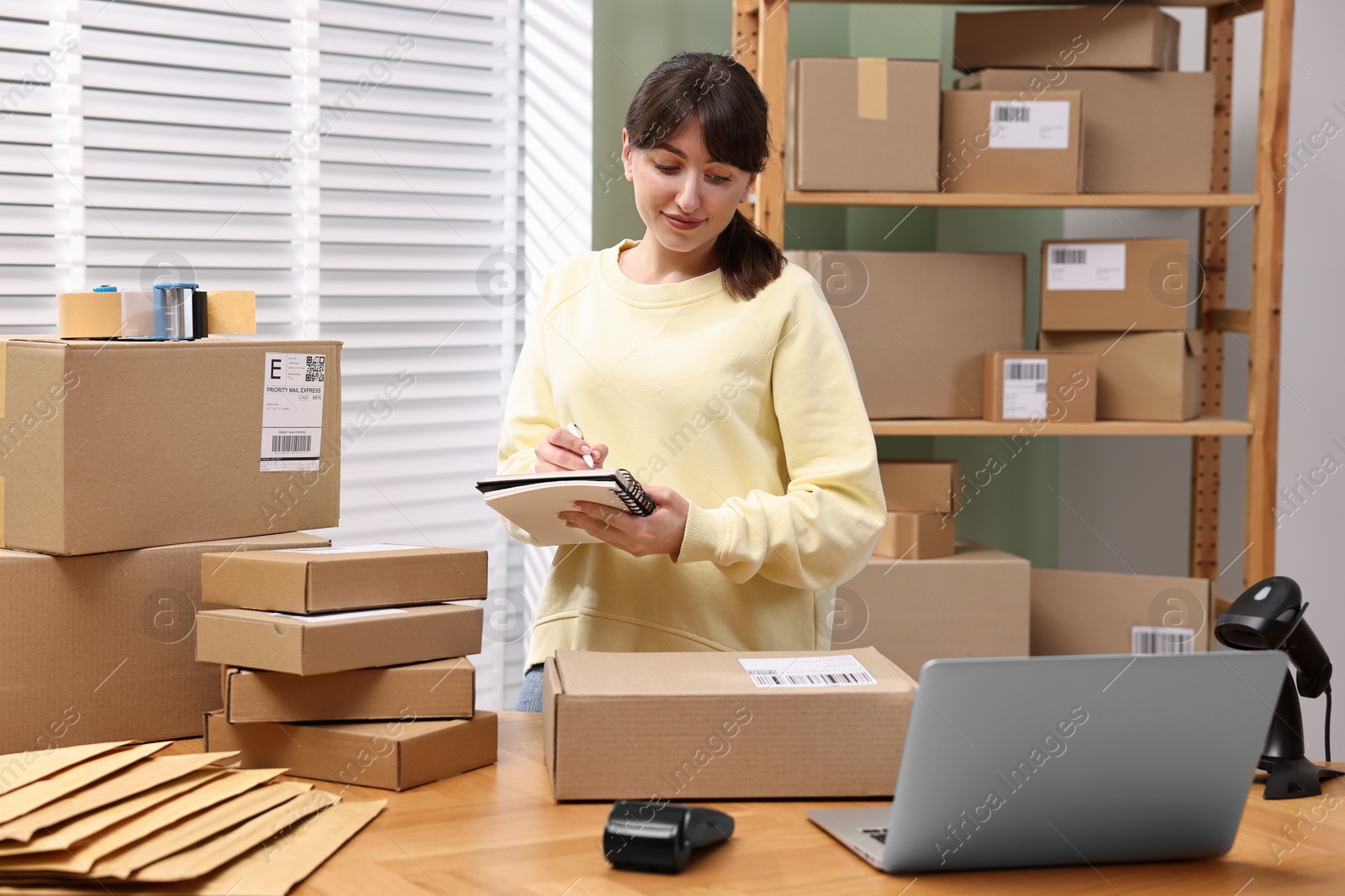 Photo of Parcel packing. Post office worker writing notes indoors